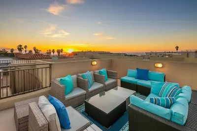 a balcony with furniture and a sunset on the beach at Stunning South Mission Home with Private Rooftop & Ocean Views! in San Diego