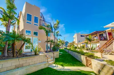 a walkway in front of a building with palm trees at Stunning South Mission Home with Private Rooftop & Ocean Views! in San Diego