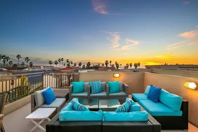 a patio with couches and tables on a balcony at Stunning South Mission Home with Private Rooftop & Ocean Views! in San Diego