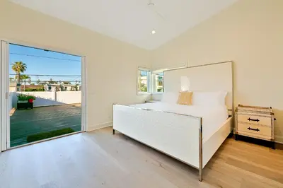 a white bedroom with a bed and a large window at Windansea Beach Luxury - Spa, AC, Walk2Beach, Garage & fast WiFi in San Diego