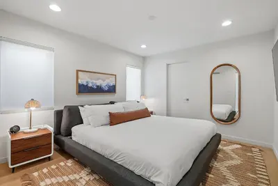 a bedroom with a large bed and a mirror at Birdrock Paradise w Private Pool& Spa, AC, fast WiFi & Yard! in San Diego