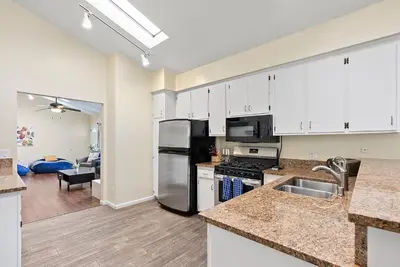 a kitchen with stainless steel appliances and a living room at Pacific Paradise - Large Patio, Hot Tub, Short Walk to Beach, & Parking in San Diego