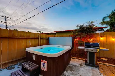 a hot tub in a backyard with a grill at Pacific Paradise - Large Patio, Hot Tub, Short Walk to Beach, & Parking in San Diego