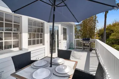 a table with plates and an umbrella on a porch at Stunning Beach Home - Steps to the Bay,Beach, &Boardwalk w Grill & Patios in San Diego