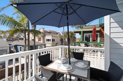 a table and chairs with an umbrella on a balcony at Stunning Beach Home - Steps to the Bay,Beach, &Boardwalk w Grill & Patios in San Diego