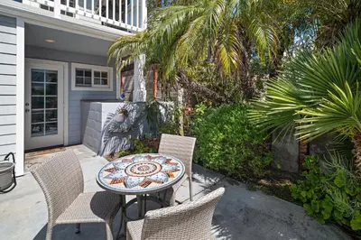 a patio with a table and chairs and palm trees at Stunning Beach Home - Steps to the Bay,Beach, &Boardwalk w Grill & Patios in San Diego