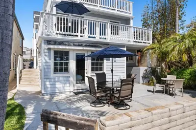 a patio with a table and chairs and an umbrella at Stunning Beach Home - Steps to the Bay,Beach, &Boardwalk w Grill & Patios in San Diego