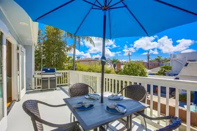 a blue table and chairs on a balcony with an umbrella at Stunning Beach Home - Steps to the Bay,Beach, &Boardwalk w Grill & Patios in San Diego