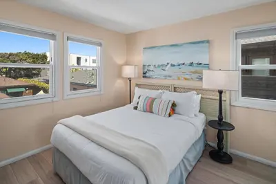 a bedroom with a bed and two windows at Bay View Paradise - Rooftop Deck, Off-Street Parking, King Suite, WasherDryer & Bay Views! in San Diego