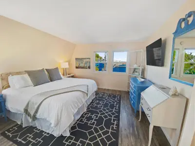 a bedroom with a bed and a desk and windows at Bay View Paradise - Rooftop Deck, Off-Street Parking, King Suite, WasherDryer & Bay Views! in San Diego