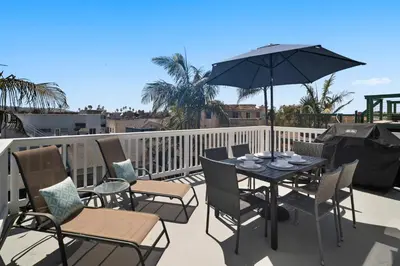 a table and chairs with an umbrella on a balcony at Bay View Paradise - Rooftop Deck, Off-Street Parking, King Suite, WasherDryer & Bay Views! in San Diego