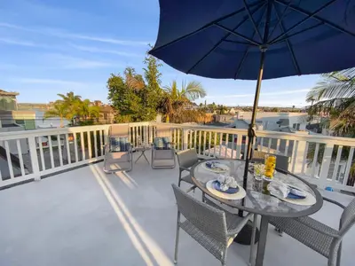 a table and chairs on a balcony with an umbrella at Bay View Paradise - Rooftop Deck, Off-Street Parking, King Suite, WasherDryer & Bay Views! in San Diego