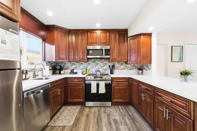 a kitchen with wooden cabinets and stainless steel appliances at Dog Friendly Home Near the Beach with Grill, Fire Pit, Enclosed Backyard in San Diego