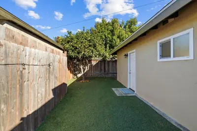 a yard next to a house with a fence at Dog Friendly Home Near the Beach with Grill, Fire Pit, Enclosed Backyard in San Diego