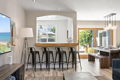 a living room with a bar with stools at Bird Rock Dreams - Ocean Views, Massive Yard, Outdoor Dining, Fast Wifi & AC! in San Diego