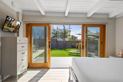 a room with a bed and a sliding glass door at Bird Rock Dreams - Ocean Views, Massive Yard, Outdoor Dining, Fast Wifi & AC! in San Diego