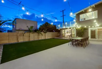 a backyard with a table and chairs and lights at Bird Rock Dreams - Ocean Views, Massive Yard, Outdoor Dining, Fast Wifi & AC! in San Diego