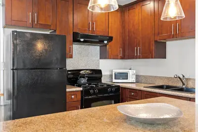 a kitchen with wooden cabinets and a black refrigerator at WindnSea Beach Perfection - Walk2Beach, Pet Friendly & Parking in San Diego