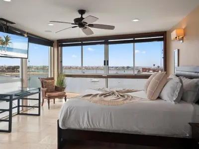 a bedroom with a bed with a ceiling fan and a table at Stunning Bayfront condo with gorgeous views, garage, massive roof deck & AC - dogs welcome! in San Diego