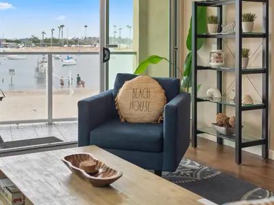 a living room with a blue chair with a pillow on a table at Stunning Bayfront condo with gorgeous views, garage, massive roof deck & AC - dogs welcome! in San Diego