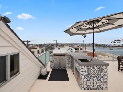 a grill on the roof of a house with an umbrella at Stunning Bayfront condo with gorgeous views, garage, massive roof deck & AC - dogs welcome! in San Diego