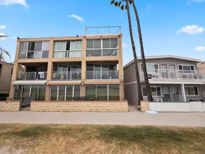 a building with a palm tree in front of it at Stunning Bayfront condo with gorgeous views, garage, massive roof deck & AC - dogs welcome! in San Diego