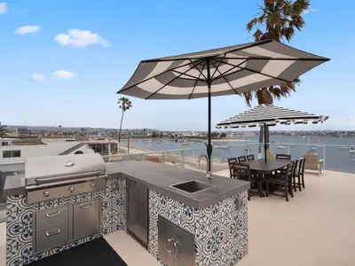 an outdoor kitchen with a grill and an umbrella at Stunning Bayfront condo with gorgeous views, garage, massive roof deck & AC - dogs welcome! in San Diego