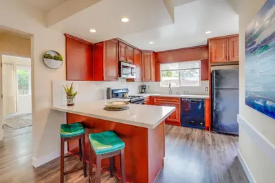 a kitchen with wooden cabinets and a counter with stools at La Jolla Oasis - Pet Friendly, Large Backyard, Walk2Beach & Location! in San Diego