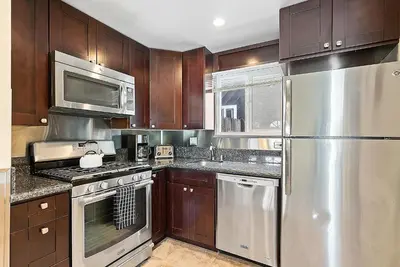 a kitchen with wooden cabinets and stainless steel appliances at Riviera Bay View Dream - Private patio with bay view and parking in San Diego