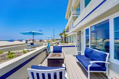 a porch with chairs and a table and an umbrella at Oceanfront Condo with Front Patio, Gas Grill, Fire Pit - Prime Location!! in San Diego