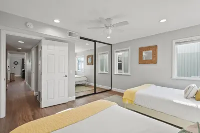a white bedroom with a bed and a mirror at Stunning Beach Home with Fireplace, Fast WiFi, Grill & Outdoor Seating! in San Diego