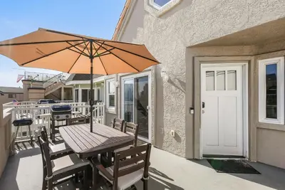 a wooden table with an umbrella on a patio at Stunning Beach Home with Fireplace, Fast WiFi, Grill & Outdoor Seating! in San Diego