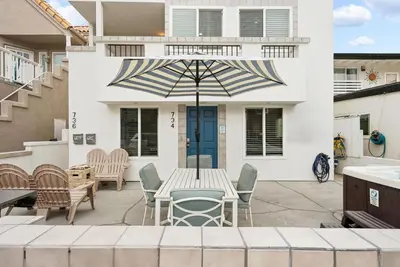 a patio with a table and chairs and an umbrella at Stunning Beach Delight with Hot Tub, Fire Pit, Parking & Walk to Beach! in San Diego