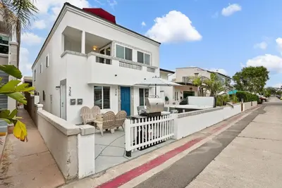 a white house with a white fence on a street at Stunning Beach Delight with Hot Tub, Fire Pit, Parking & Walk to Beach! in San Diego