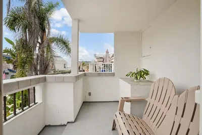 a balcony with a table and chairs and a window at Beach Perfection - Ocean Views, Parking, Pet Friendly & Steps2Sand in San Diego