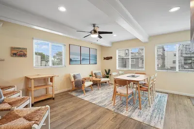 a living room with a table and chairs and windows at Beach Perfection - Ocean Views, Parking, Pet Friendly & Steps2Sand in San Diego