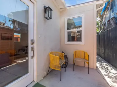 two chairs sitting on a porch next to a door at Beach Bungalow Perfection - Private Patios, BBQ walk2beach & Pet Friendly! in San Diego
