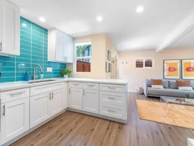 a kitchen with white cabinets and a living room at Beach Bungalow Perfection - Private Patios, BBQ walk2beach & Pet Friendly! in San Diego