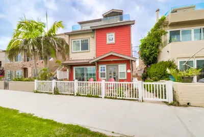 a red house with a white fence at Bayfront Paradise- Bay Views & Boardwalk Patio in San Diego