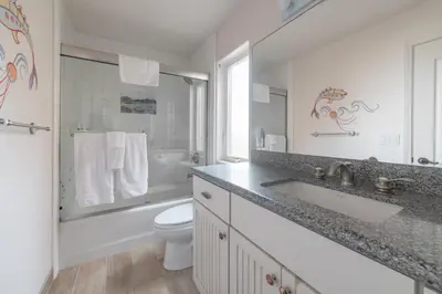 a white bathroom with a sink and a toilet at Bayfront Paradise- Bay Views & Boardwalk Patio in San Diego