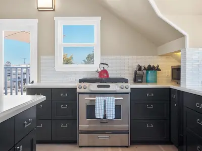 a kitchen with black cabinets and a stainless steel oven at Kennebeck Views - Ocean View, Roof Patio, Steps to Beach & Boardwalk in San Diego