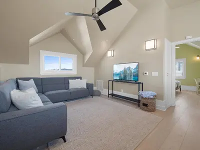 a living room with a blue couch and a ceiling fan at Kennebeck Views - Ocean View, Roof Patio, Steps to Beach & Boardwalk in San Diego