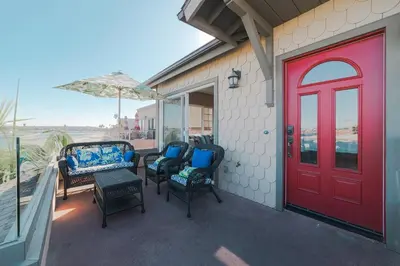 a porch with a red door and chairs and an umbrella at Bayfront Dream - Bay Views, Rooftop Patio, & Garage! in San Diego