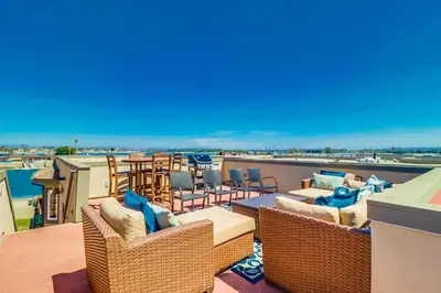a balcony with wicker chairs and tables on a roof at Bayfront Dream - Bay Views, Rooftop Patio, & Garage! in San Diego