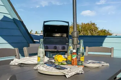 a table with plates and bottles and a grill at Ormond Retreat w Ocean View, Steps2beach & Garage in San Diego
