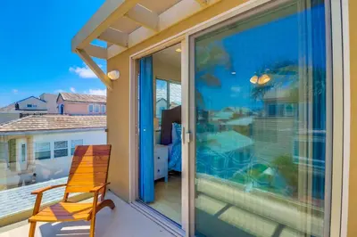 a chair sitting on a balcony with a large window at Beach Oasis - Rooftop, Steps2Sand and Water Views in San Diego
