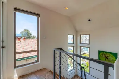a staircase in a house with a large window at Beach Oasis - Rooftop, Steps2Sand and Water Views in San Diego