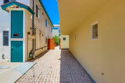 an alley between two buildings with a blue door at Beach Oasis - Rooftop, Steps2Sand and Water Views in San Diego