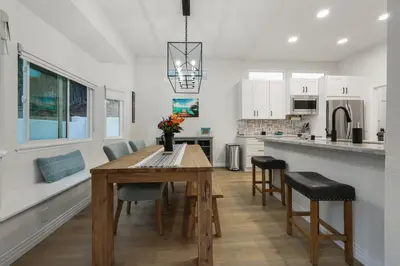 a kitchen and dining room with a wooden table and chairs at Modern Dream Home - Fire Pit, Grill, Large Yard & AC in Encinitas