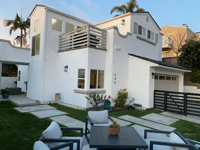 a white house with a table and chairs in the yard at Modern Dream Home - Fire Pit, Grill, Large Yard & AC in Encinitas